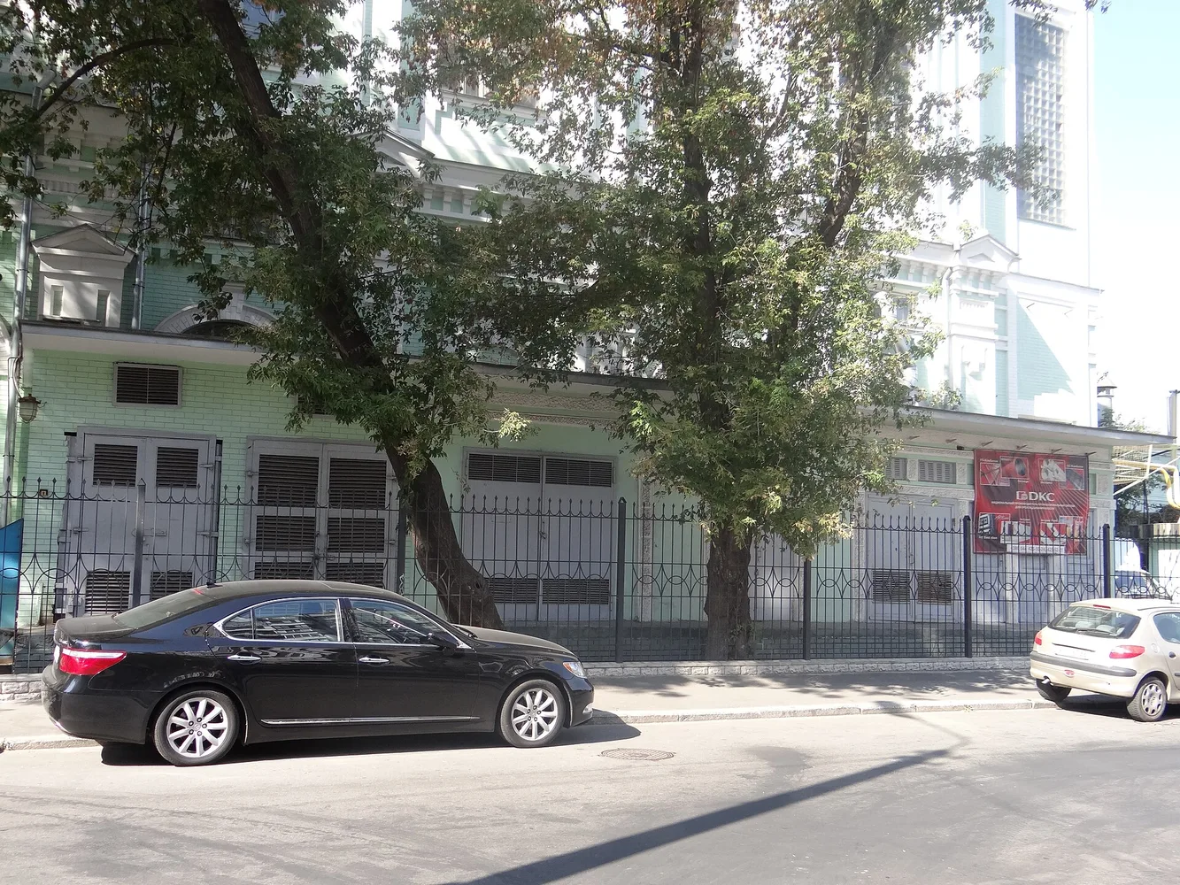 Фасад розподільної електропідстанції біля вулиці, припарковані автомобілі вздовж тротуару