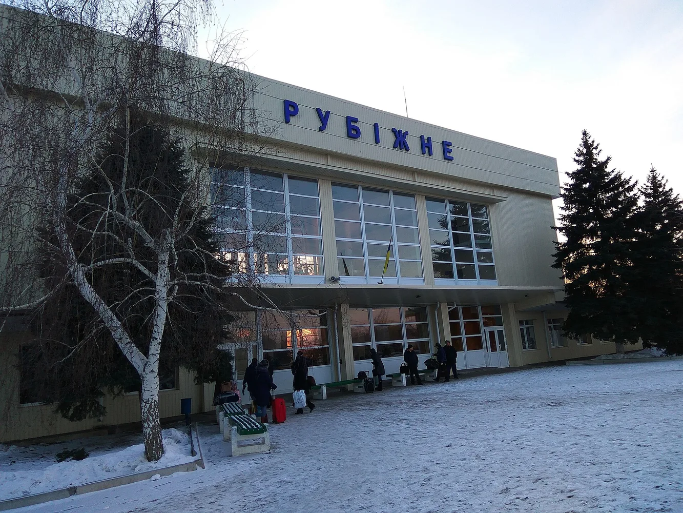 Фасад залізничного вокзалу з написом «РУБІЖНЕ», люди на платформі, зимовий майданчик зі снігом