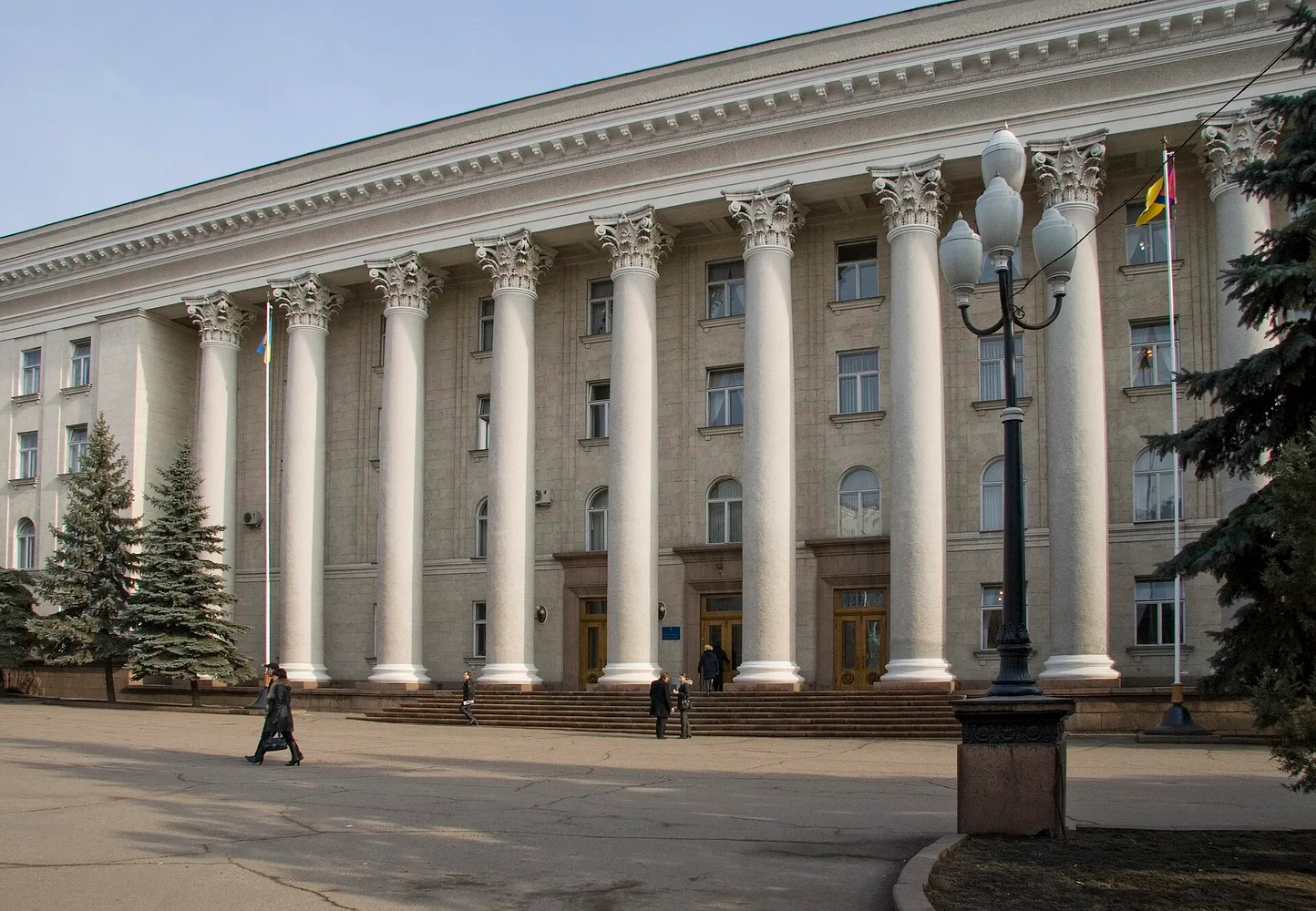 Фронтальний план будівлі Кіровоградської (Кропивницької) міської ради/мерії з колонами, входом і кількома людьми біля сходів.